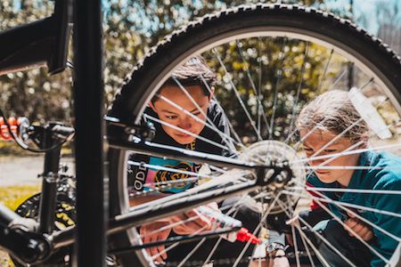 two middle schoolers examining a bike tire