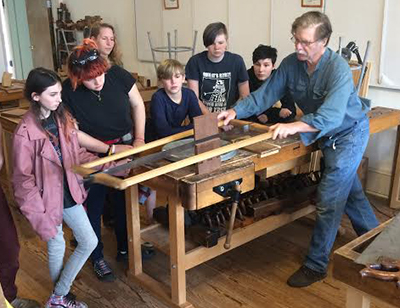 middle schoolers watching a wood worker
